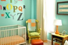 a bold vintage nursery with turquoise walls, a yellow chair and a nightstand, orange rugs, bold textiles and bright letters