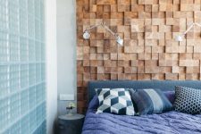 a bright bedroom with a wood square accent wall, an upholstered bed, bright blue bedding and geometric pillows is amazing