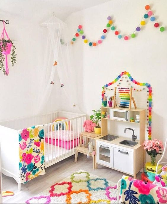a bright nursery with all white everything spruced up with bold linens, rugs and garlands looks amazing