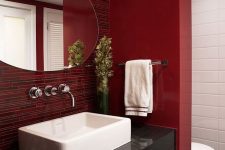 a bright red bathroom with catchy tiles on the wall and a space divider, white appliances and lights here and there