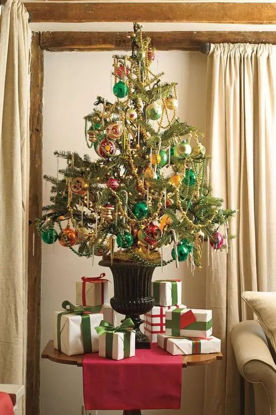 a bright vintage-inspired Christmas tree in an urn, decorated with pink, emerald and orange ornaments and beaded garlands