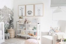 a catchy neutral nursery in white and grey, with a printed wall, a gallery wall with artworks, a shelving unit, white furniture, a pink ottoman and grey textiles