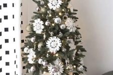 a chic and shiny tabletop Christmas tree with lights, silver and gold glitter ornaments, white paper snowflakes and a star topper