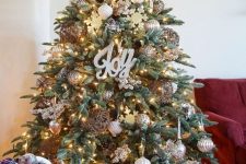 a chic farmhouse Christmas tree with lights, calligraphy, metallic ornaments, pinecones, snowflakes and with a metal base