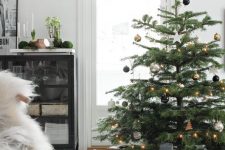 a chic modern Christmas tree with lights, gold, black and silver ornaments plus a star topper and lots of gifts