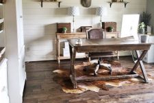 a chic rustic home office with a wooden trestle desk, a wooden console, lamps, shelves and some vintage table lamps