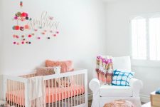a colorful nursery with white furniture and bold bedding, rugs, pillows and colorful pompoms on the wall
