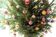 a colorful tabletop Christmas tree decorated with pink and yellow ornaments and nothing else is modern and bold