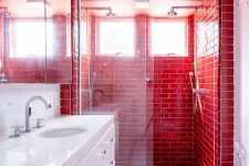 a contemporary red and white bathroom clad with subway tiles, with a sleek white vanity and appliances is a bold and gorgeous space