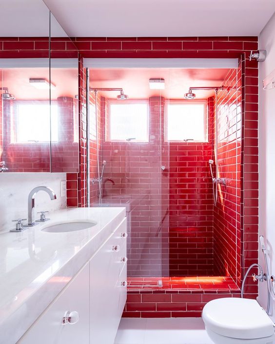 a contemporary red and white bathroom clad with subway tiles, with a sleek white vanity and appliances is a bold and gorgeous space
