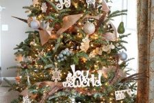 a cool rustic Christmas tree with lights, vine, burlap ribbons, silver ornaments, snowflakes and feathers
