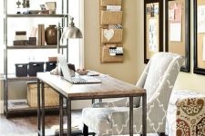 a cozy warm-colored rustic home office with tan walls, a wooden desk and a matching open shelf, printed upholstered furniture and some potted plants