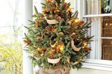 a fantastic rustic tabletop Christmas tree decorated with lights, pinecones and burlap ribbons is easy to repeat in your backyard