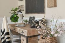 a farmhouse home office with a desk of wood and metal, baskets on the wall, a chalkboard and a cool white chair