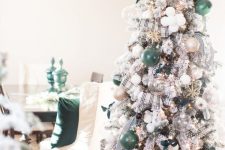 a flocked Christmas tree with sheer, white, green and gold glitter ornaments, with plaid ribbons and fresh greenery on top