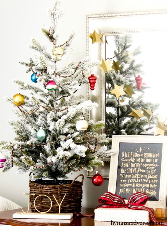 a flocked tabletop Christmas tree decorated with colorful vintage ornaments is a lovely decor idea for the holidays