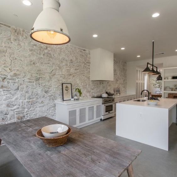 a kitchen and dining zone done in modern farmhouse style with a whitewashed stone accent wall that sets the tone and atmosphere here