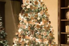 a luxurious rustic Christmas tree with lights, white and brown ornaments, snowy pinecones, deer, snowflakes and beads is wow