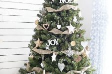 a modern rustic Christmas tree with burlap ribbons, wooden ornaments shaped as hearts, stars and snowflakes and a basket base