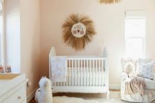a neutral boho nursery with white furniture, a lion artwork, a tassel chandelier, layered rugs and printed textiles