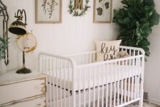 a neutral boho nursery with white shabby chic and modern furniture, layered rugs, a gallery wall and some plants is very cool