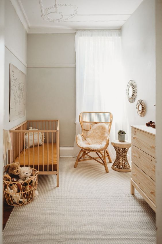 a neutral boho nursery with wicker furniture, a plywood dresser, mirrors and a basket with toys is a cozy idea