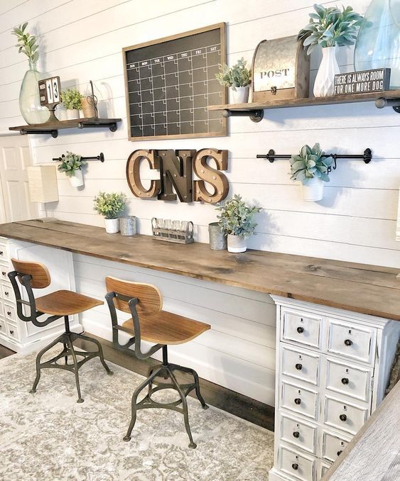 a neutral farmhouse home office with open shelves, a shared desk with white cabinets, a chalkboard and marquee letters on the wall