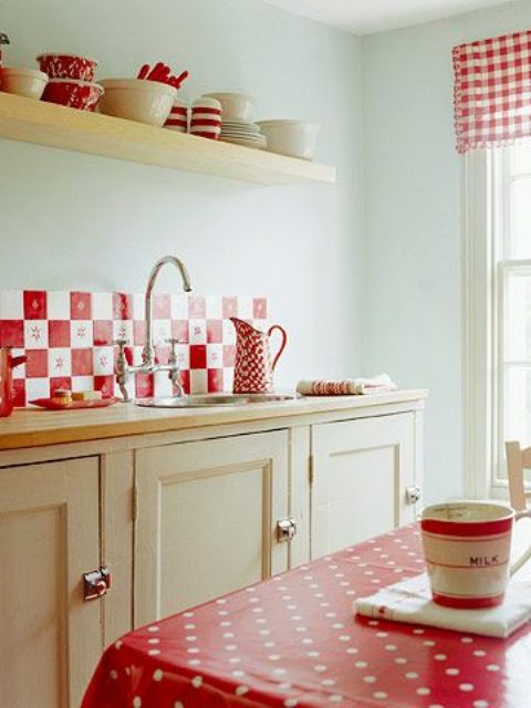 a neutral warm toned kitchen with a red tile backsplash, linens and textiles and bold red tableware feels cozy and vintage