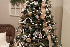 a pretty rustic Christmas tree with burlap ribbons, pompom garlands, twine balls, snowflakes and branches