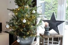 a pretty tabletop Christmas tree in a bucket with lights and white ornaments is perfect for a rustic Christmas space