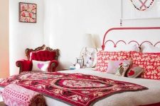 a refined bedroom with a mattress bed, a refined red chair, a pendant lamp and bright printed red bedding