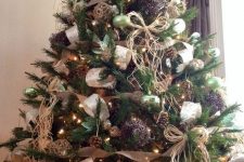 a rustic Christmas tree with lights, pinecones, burlap and printed ribbons, twine balls and twine bows plus a wooden star topper
