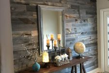 a rustic entryway with a reclaimed wooden wall, a trestle console, a mirror, baskets for storage and candles on the table