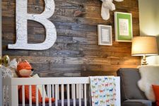 a rustic nursery with a dark stained wooden wall, neutral furniture, faux taxidermy and colorful bedding is a bright and welcoming space