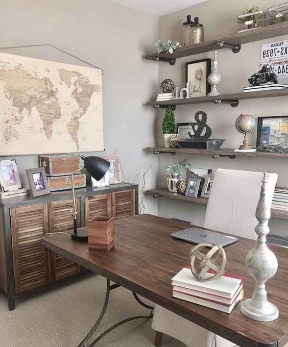 a rustic vintage home office with open industrial shelving, a wood and metal desk, a shutter sideboard and maps and artworks