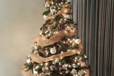 a simple rustic Christmas tree with lights, white and gold ornaments, burlap ribbons, snowy pinecones, a vine star topper