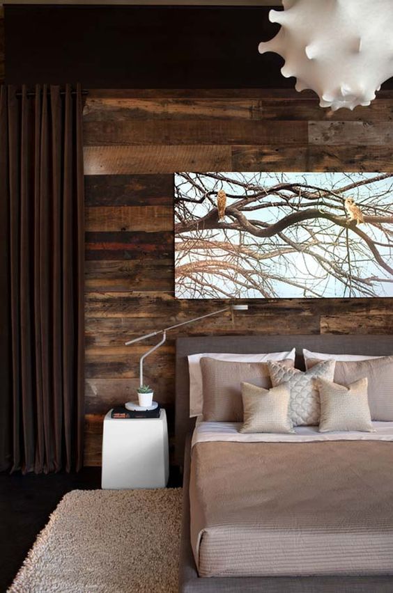 a stylish modern bedroom in shades of brown is added interest with a reclaimed wood wall that brings coziness and warmth to the room