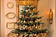 a tabletop Christmas tree decorated with gold ornaments and lights is a cool and catchy decoration