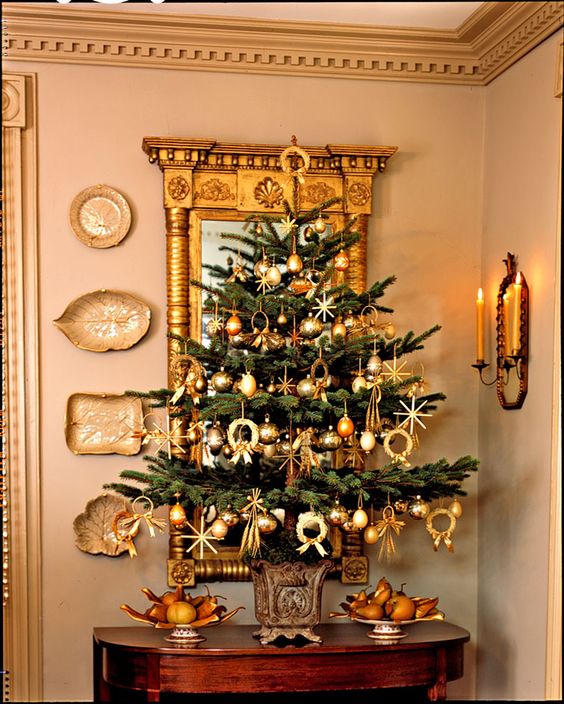a tabletop Christmas tree decorated with gold ornaments and lights is a cool and catchy decoration