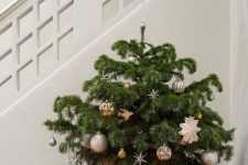 a tabletop Christmas tree in a basket with metallic and whimsical ornaments is a stylish idea for the holidays