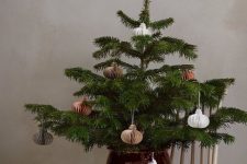 a tabletop Christmas tree in a shiny burgundy planter, with paper ornaments for a stylsih modern space