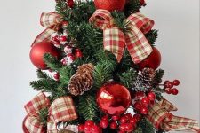 a tabletop Christmas tree with berries, pinecones, red ornaments and red plaid bows is a cool and catchy decoration