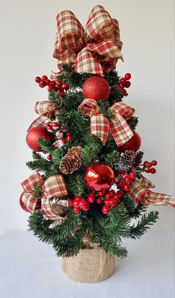 a tabletop Christmas tree with berries, pinecones, red ornaments and red plaid bows is a cool and catchy decoration