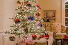 a tabletop Christmas tree with lights and oversized painted ornaments plus a colorful bow on top