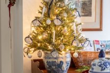 a tabletop Christmas tree with lights and white and navy ornaments with ribbons is amazing