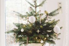 a tabletop Christmas tree with lights, candy canes and white paper bauble ornaments is a cool and lovely decoration