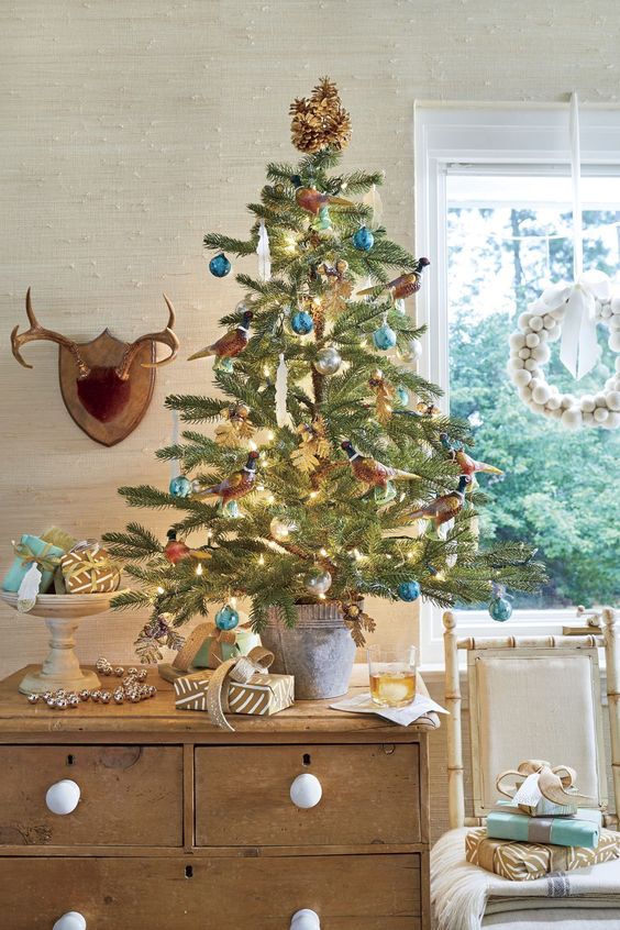 a tabletop Christmas tree with lights, faux birds, brown and blue ornaments and icicles is a cool idea
