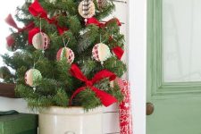 a tabletop Christmas tree with paper ornaments and red bows is a cool and catchy decoration for the holidays