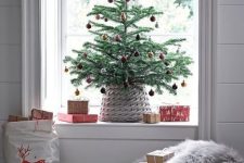 a tabletop Christmas tree with red ornaments and a basket is a cool idea for a bold modern space