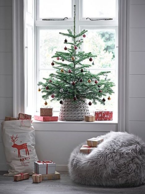 a tabletop Christmas tree with red ornaments and a basket is a cool idea for a bold modern space